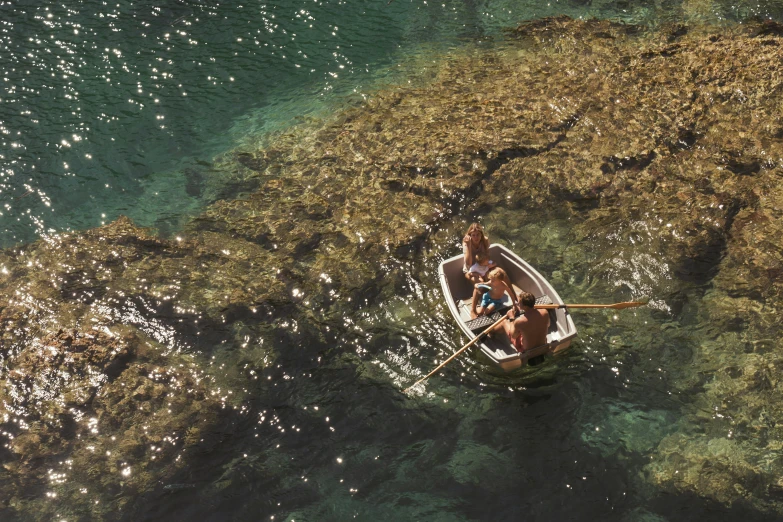 two people paddling in a small rowboat near rocks