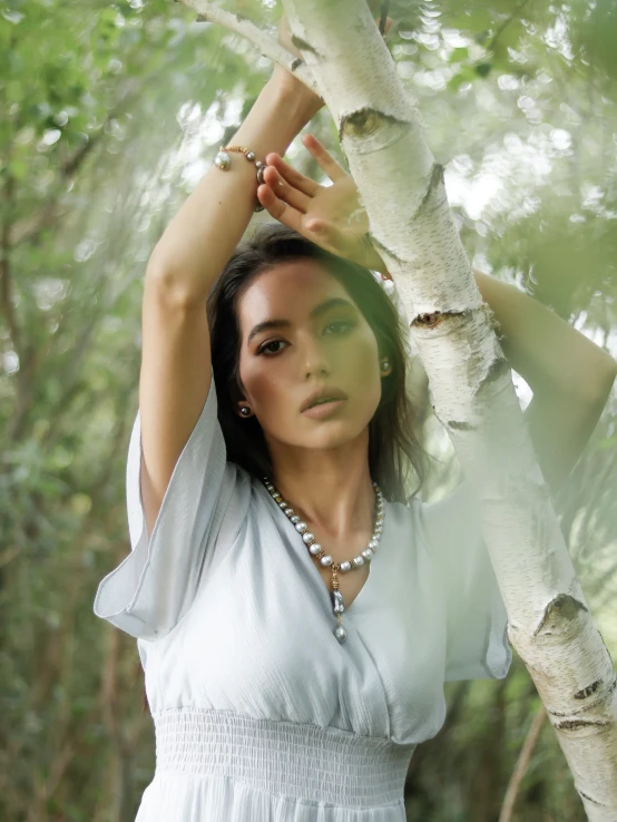 a beautiful woman standing next to a tree