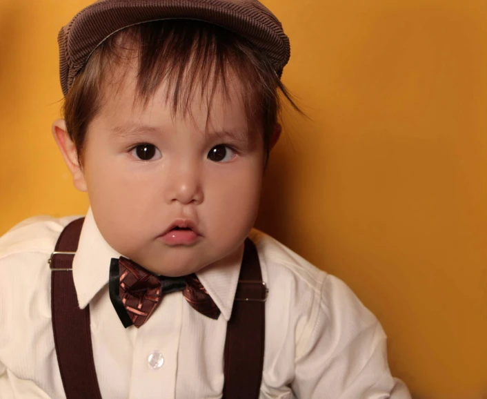 an adorable little  with a brown hat and suspenders