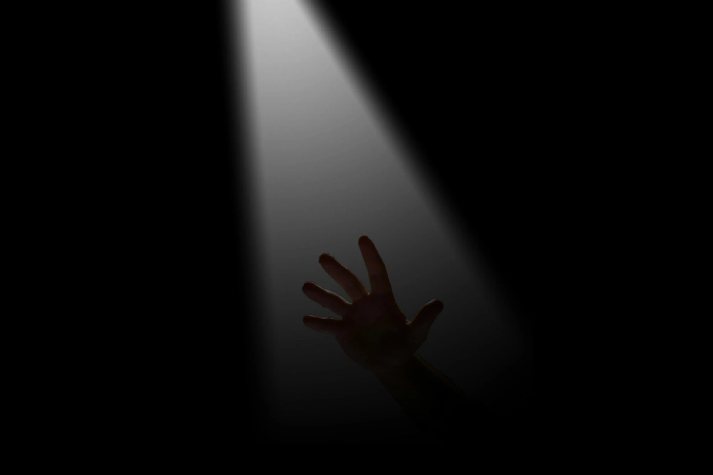 hands coming out from a dark room with a spot on the floor