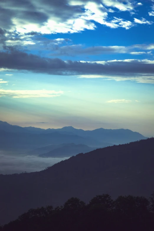 a view of clouds and mountains under a blue cloudy sky