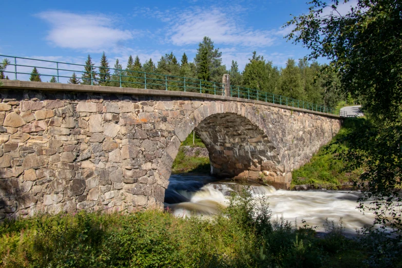 stone bridge over a fast flowing river on a sunny day