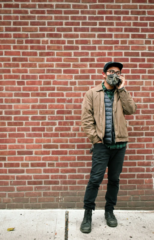 man in hat and jacket wearing face mask posing on sidewalk