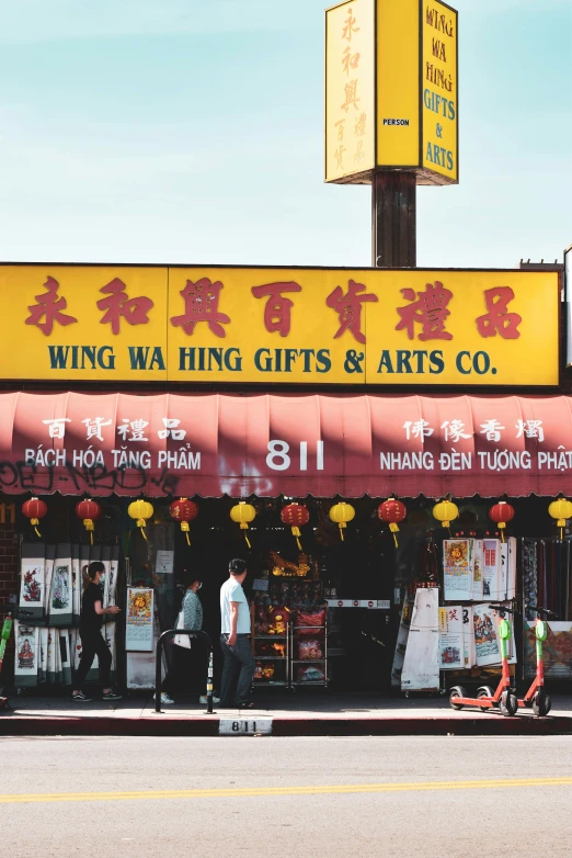 people walk by a chinese shop selling various things