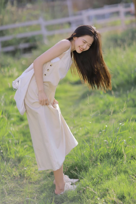 an asian woman wearing a white dress standing in a field