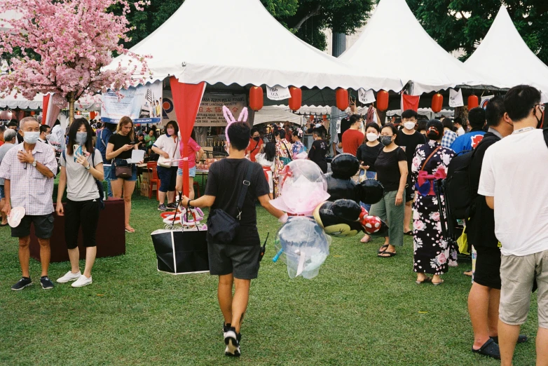 people walk through a crowd near tented booths