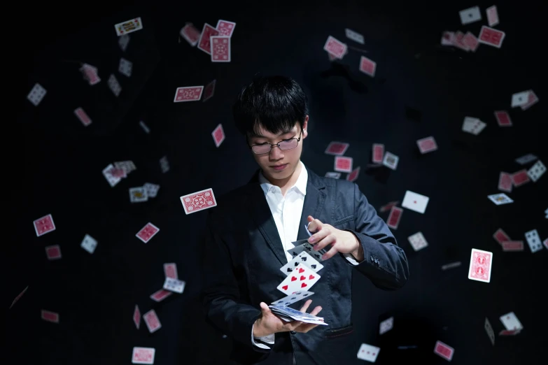 an asian man is holding onto his cards with falling sheets of red and white