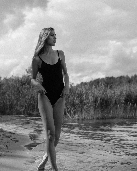 a young woman walking along the beach in a bathing suit
