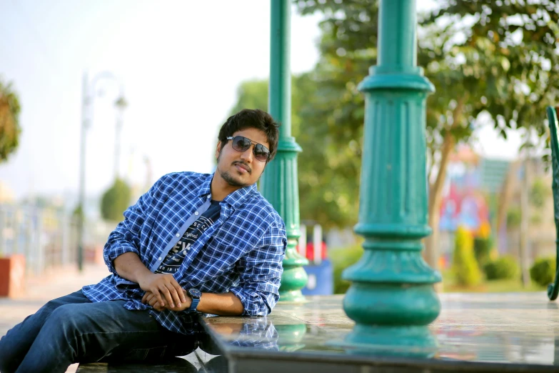 a man sitting on a green post by the street