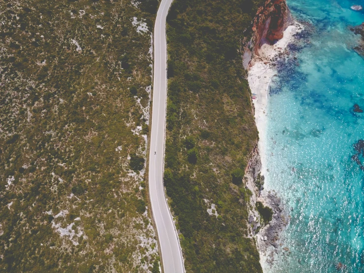 an aerial po of a paved road in the middle of the sea