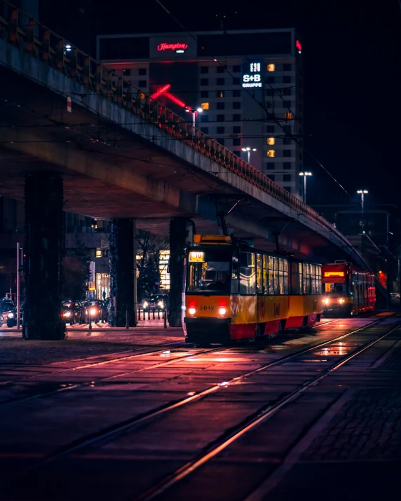 a train passes under an illuminated bridge in the dark