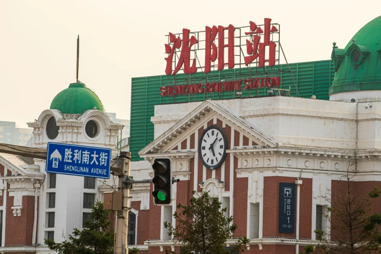 a clock and a green traffic light next to some large buildings