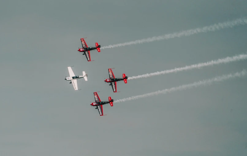 four airplanes are flying through the gray sky