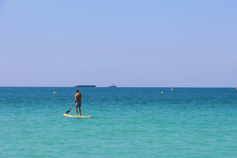 a man is standing on his surf board with the water behind him