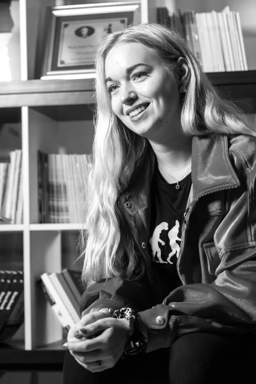 a young blonde haired woman sitting in a chair smiling