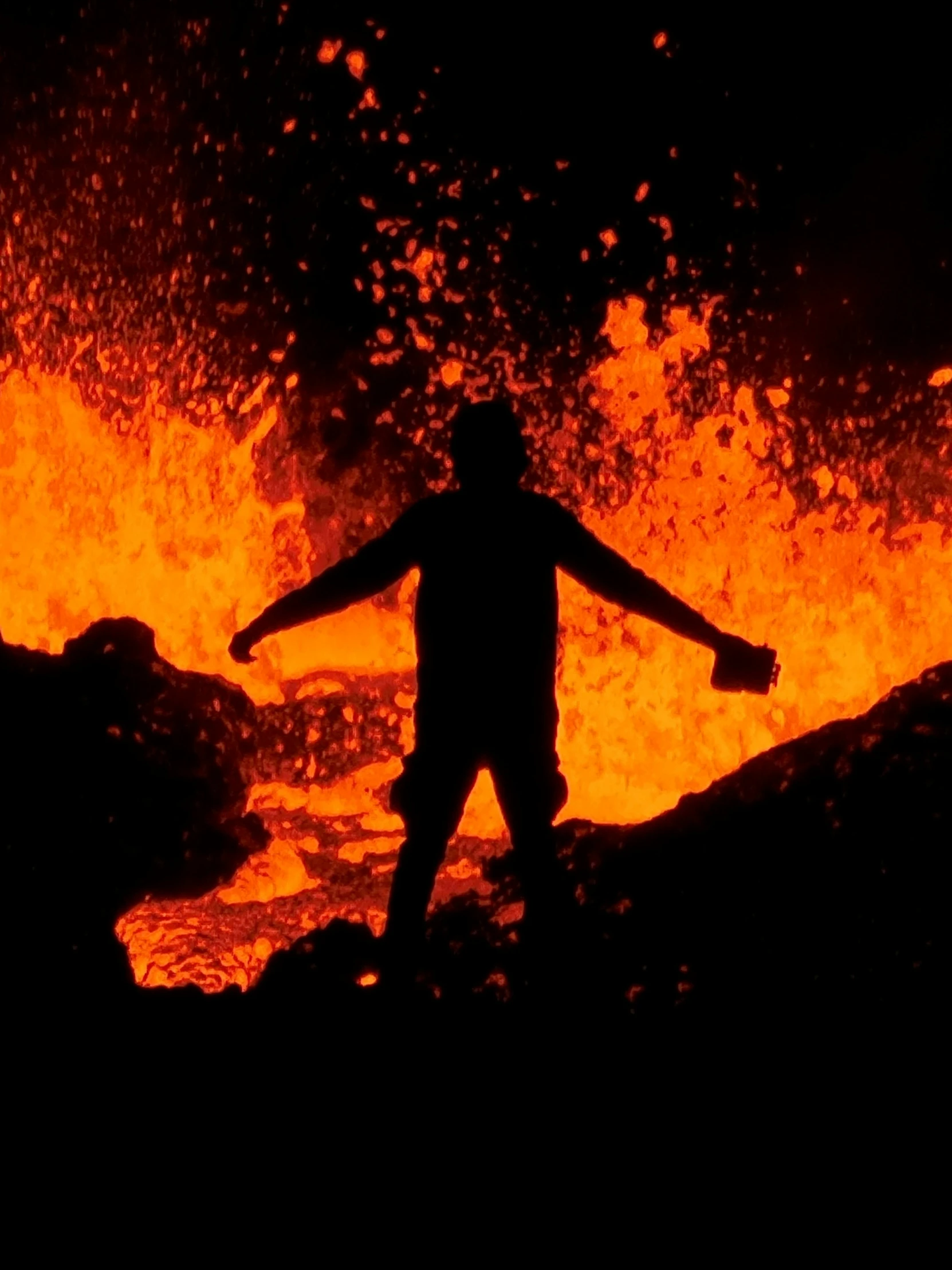 a man standing in front of a large fire on a field