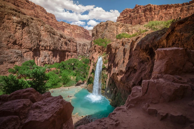 a tall waterfall has blue water between the cliffs