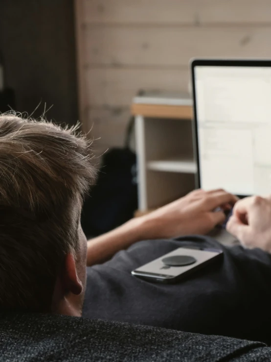 a boy with his arm over a laptop and a remote control