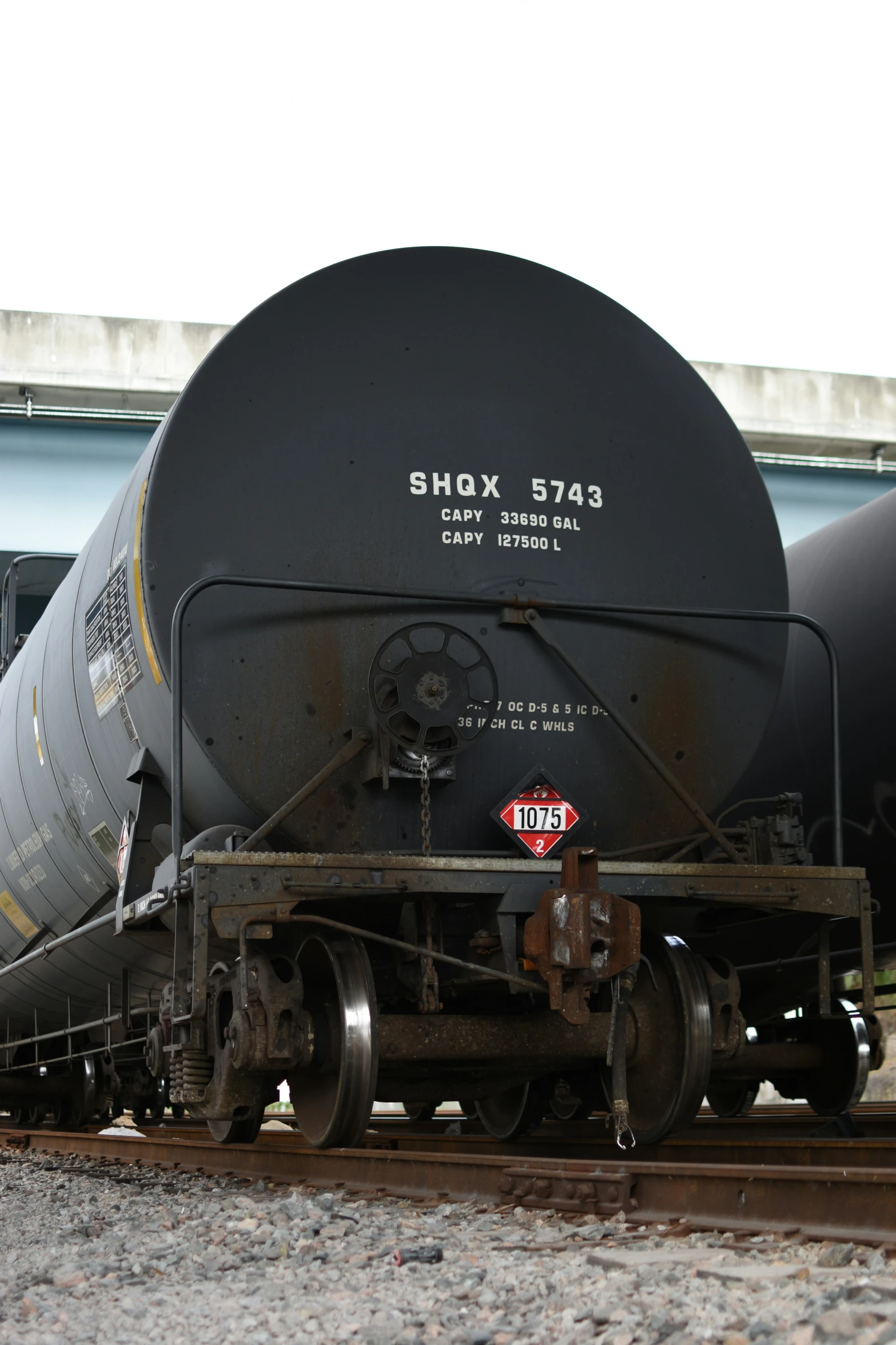 black tanker car on tracks by blue building