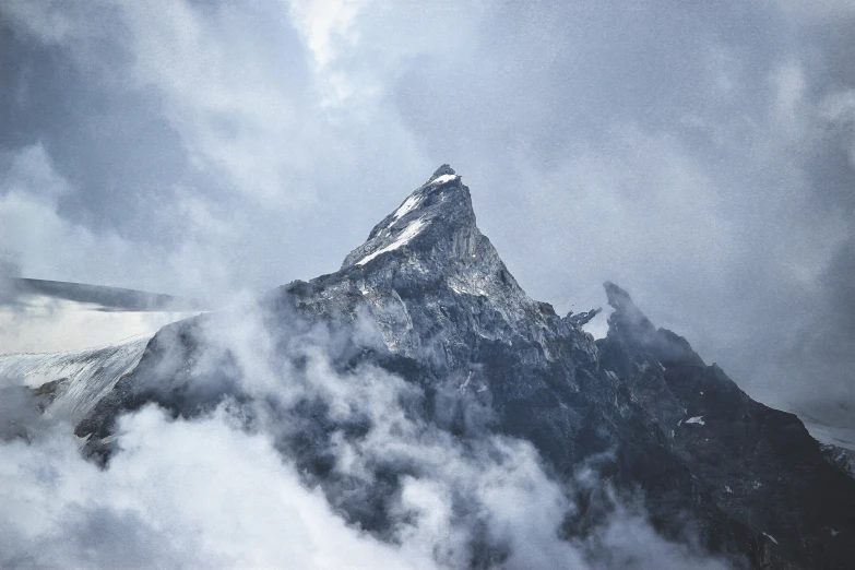 a snowy mountain is shown in the midst of clouds