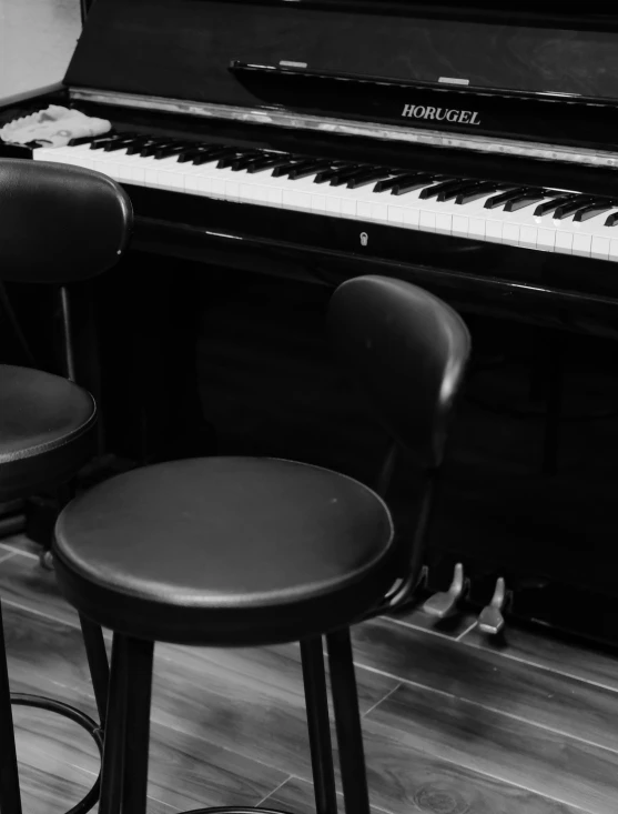 two stools next to a black piano in a room