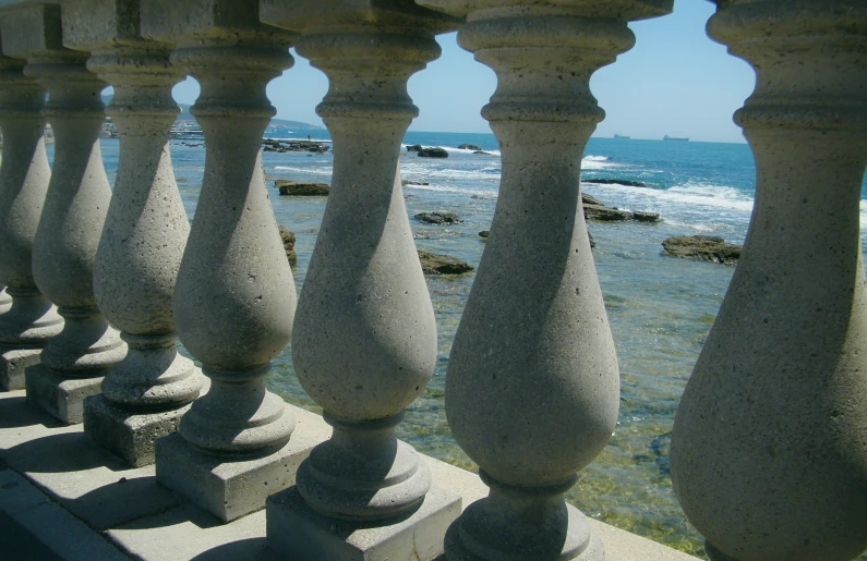 a row of stone columns with the ocean in the background