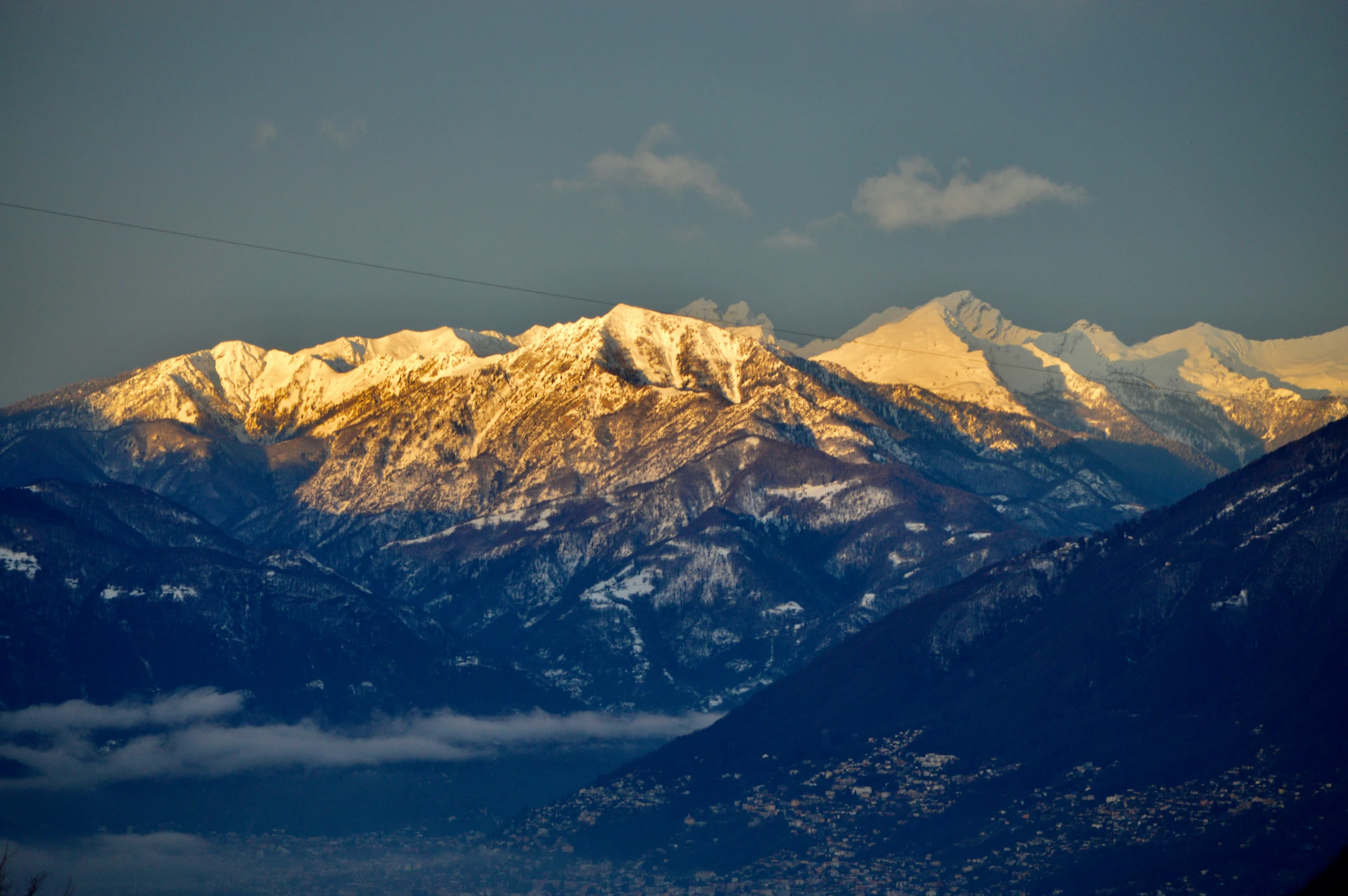 mountain range covered in snow as the sun goes down