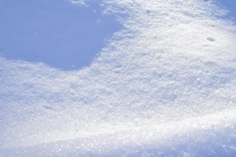 snow is falling off the edge of a snowy surface