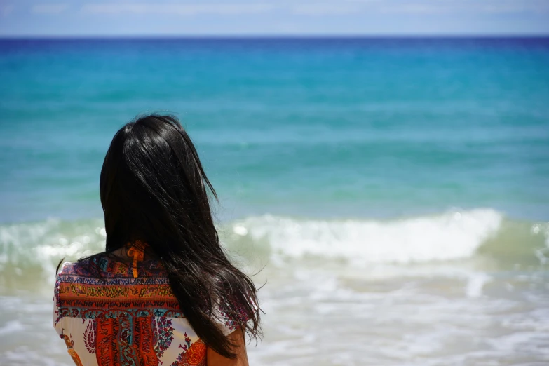 a woman looking out over the water of a beach