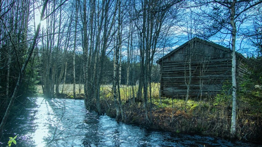 an old wood cabin on the banks of a stream