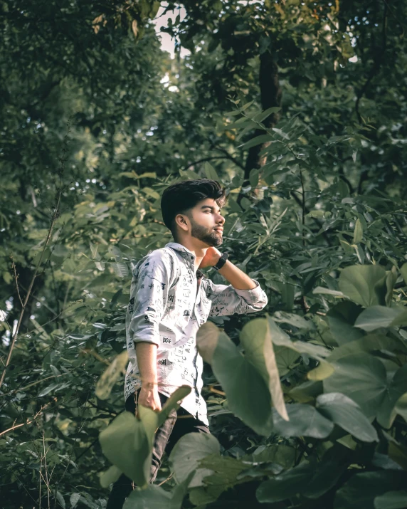 a man standing in a dense forest holding a glass