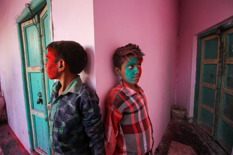 two boys standing next to each other while they both paint their faces pink