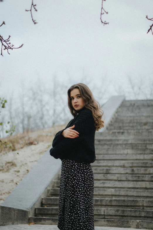 a pregnant woman wearing a long skirt standing in front of a staircase