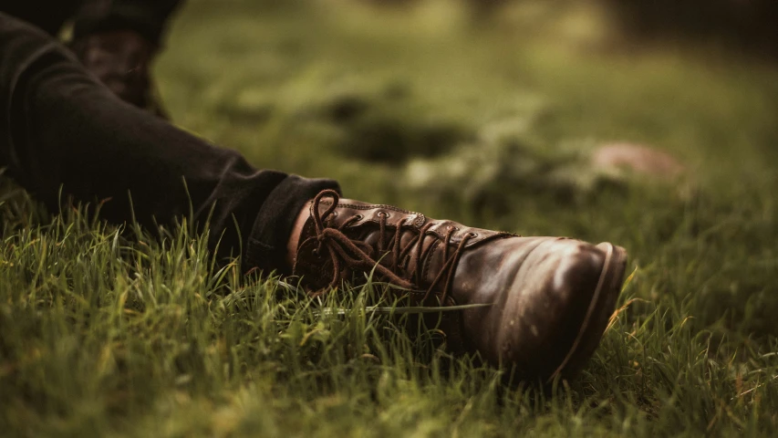 a close up of a person wearing boots sitting on grass