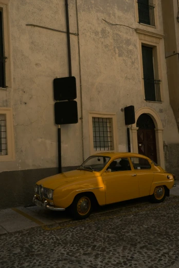an old vintage yellow car is parked on the street