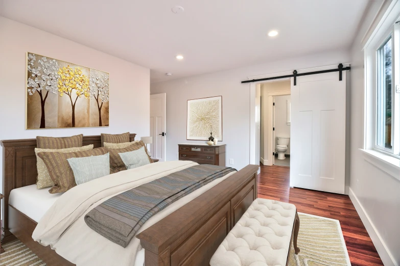 a bed room with a neatly made bed and hardwood floors