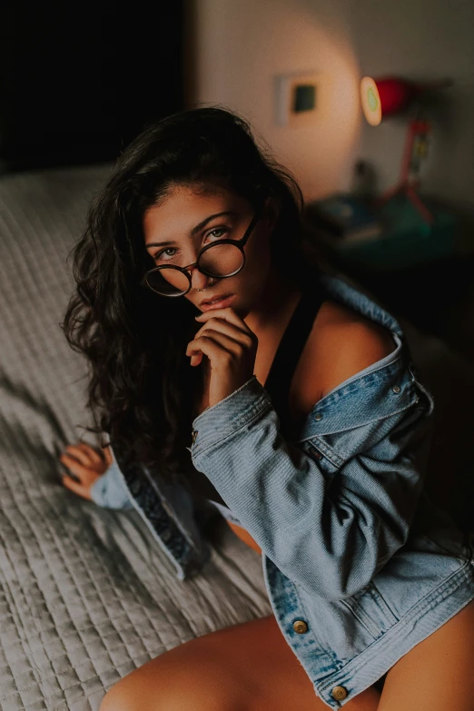 a woman sitting on her bed wearing glasses and smiling