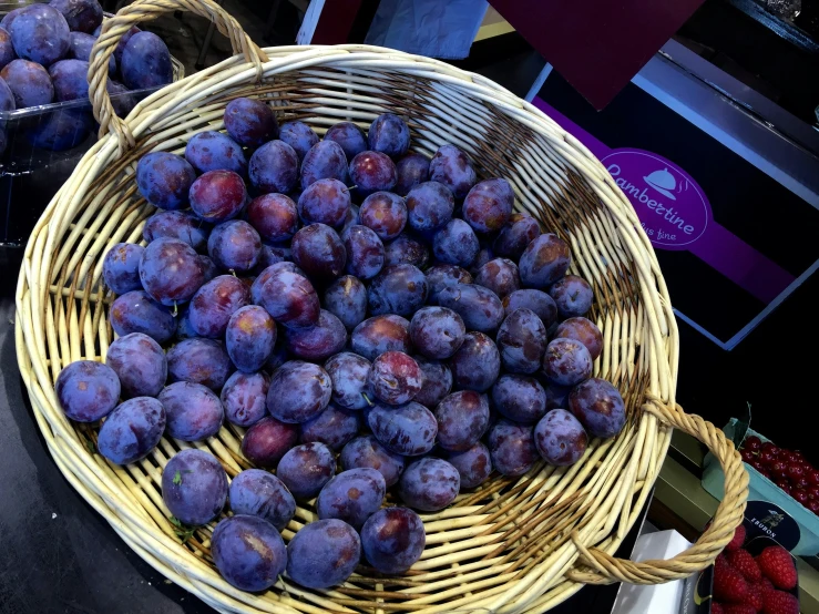 basket of plums at outdoor stall on table