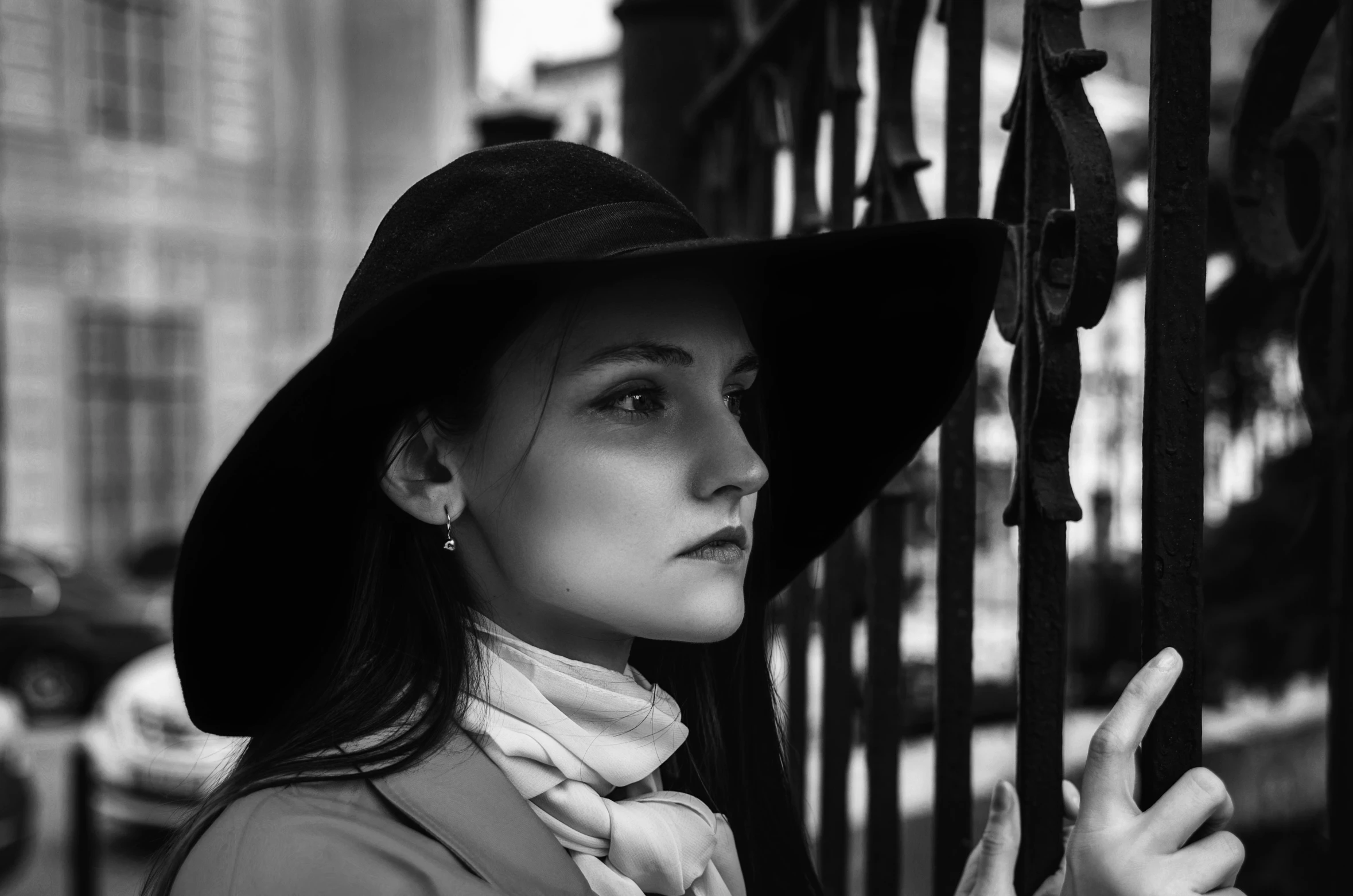 a woman wearing a hat and looking into the distance behind a gate