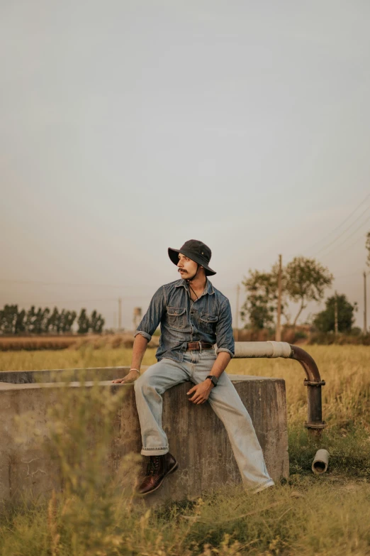 man wearing a cowboy hat sitting on a wall