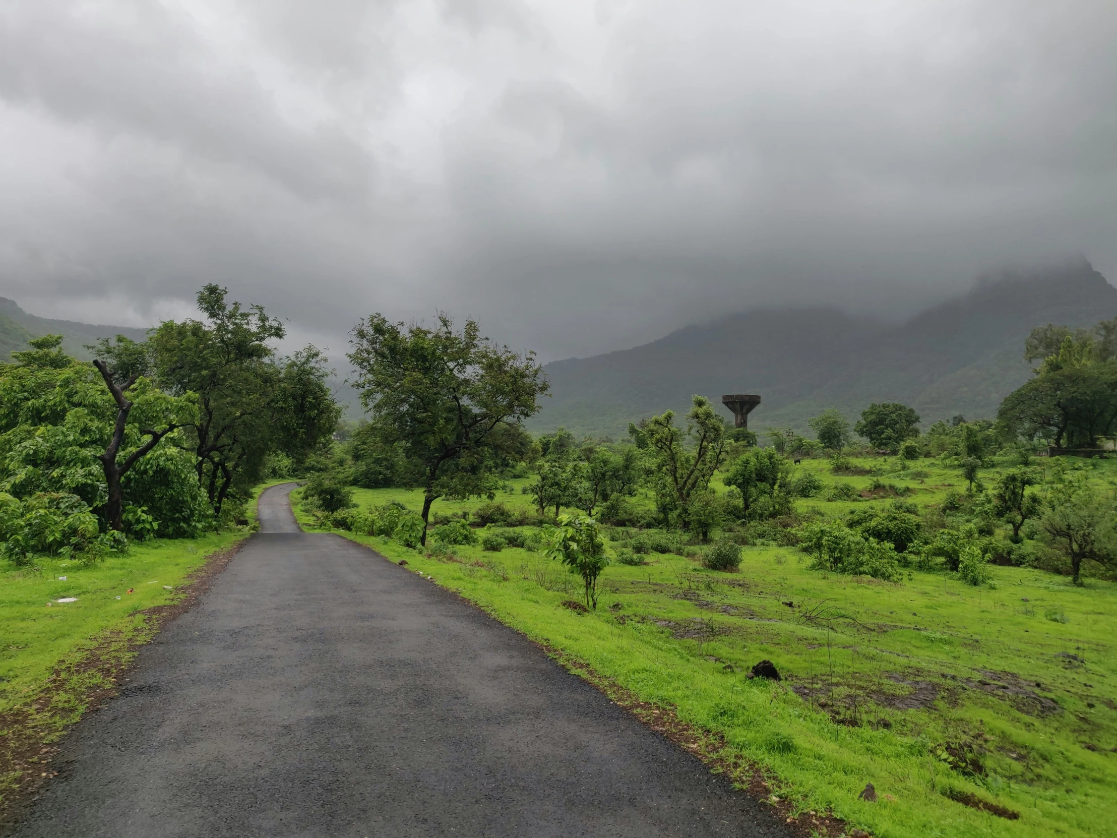 the paved road in front of the mountains under the clouds