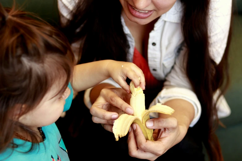 a little girl and a lady holding some bananas