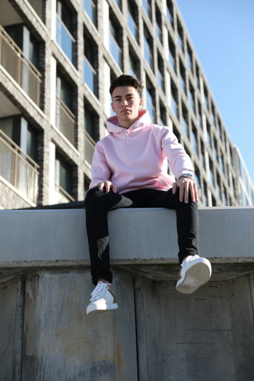 a man sitting on the wall in a pink hoodie