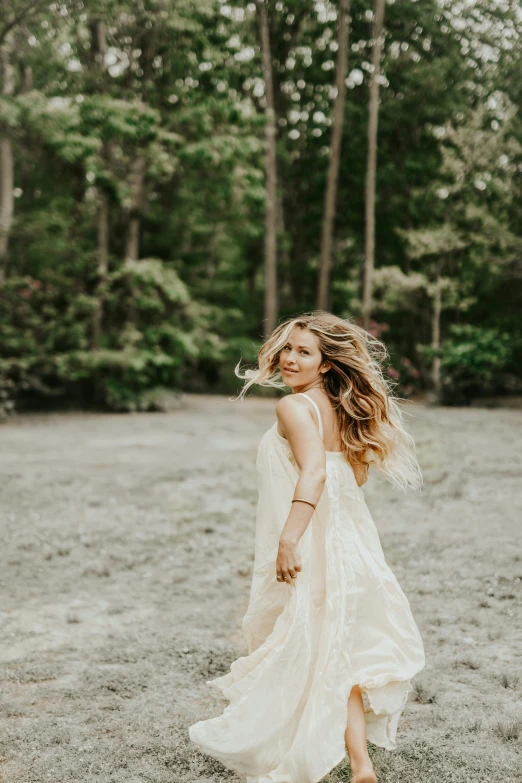 a woman in a white dress standing in a dirt field