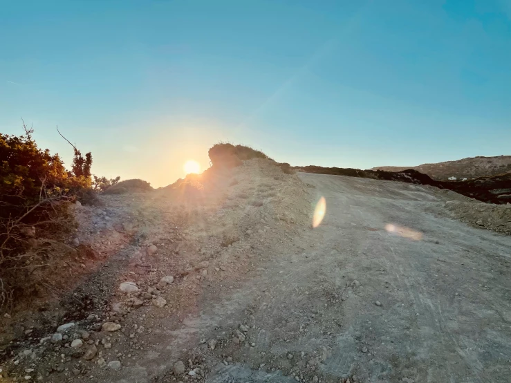 the sunset illuminates a very pretty, colorful view from the top of a dirt road