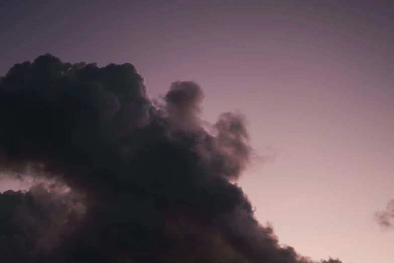 a plane is flying over the horizon and a smoke plume