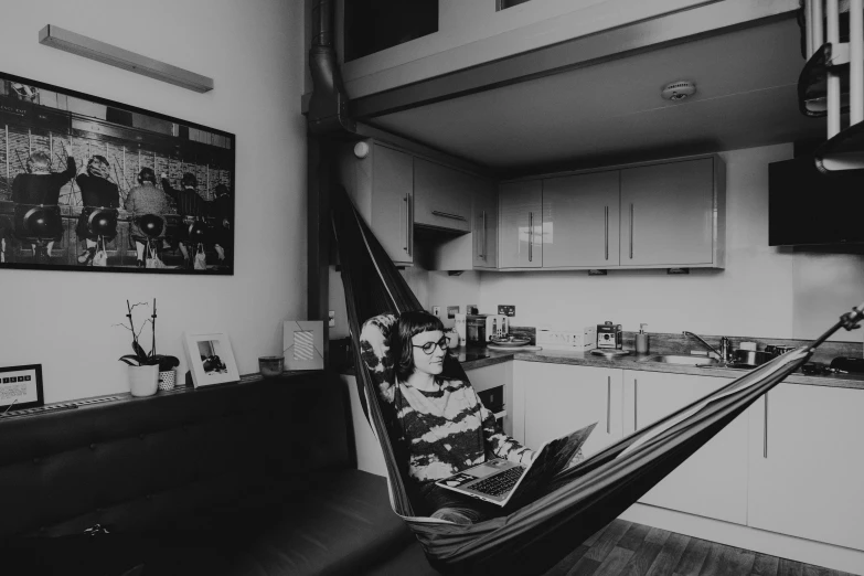 a woman sitting in a hammock reading a newspaper