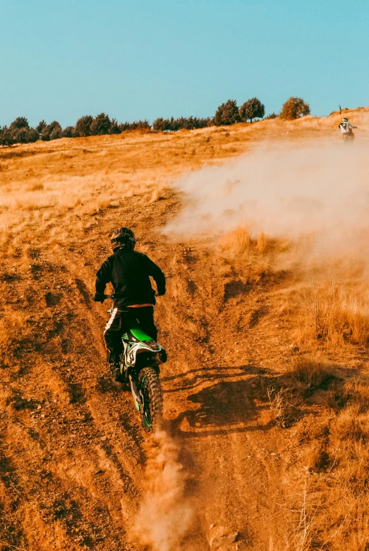 dirt bike rider on path near dust cloud