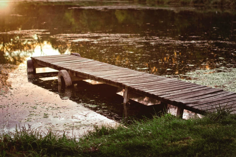 a wooden dock sitting in the water next to grass