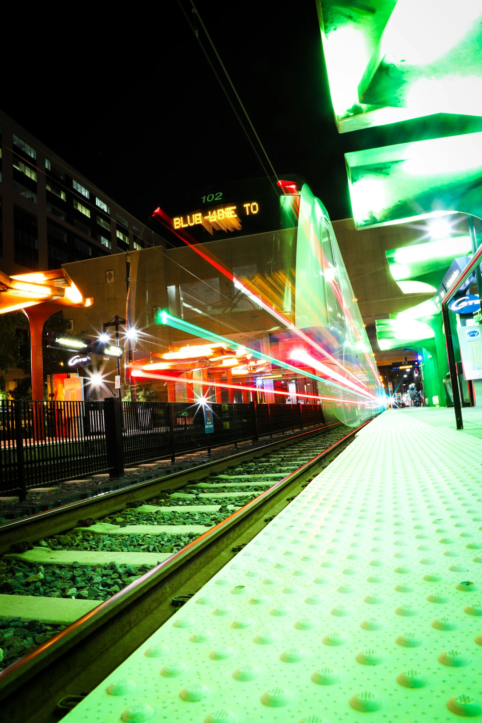 a colorful train coming down the tracks at night